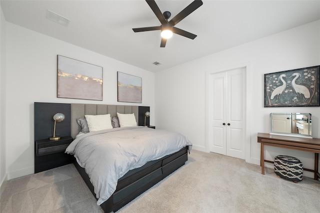 bedroom with a closet, ceiling fan, and light carpet