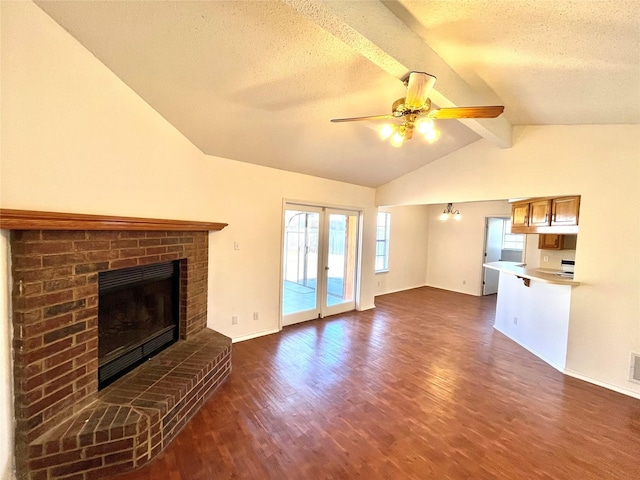 unfurnished living room with french doors, vaulted ceiling with beams, a fireplace, and a textured ceiling