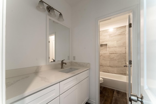 full bathroom with hardwood / wood-style flooring, toilet, vanity, and tiled shower / bath combo