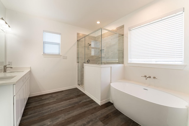 bathroom featuring hardwood / wood-style flooring, plus walk in shower, and vanity