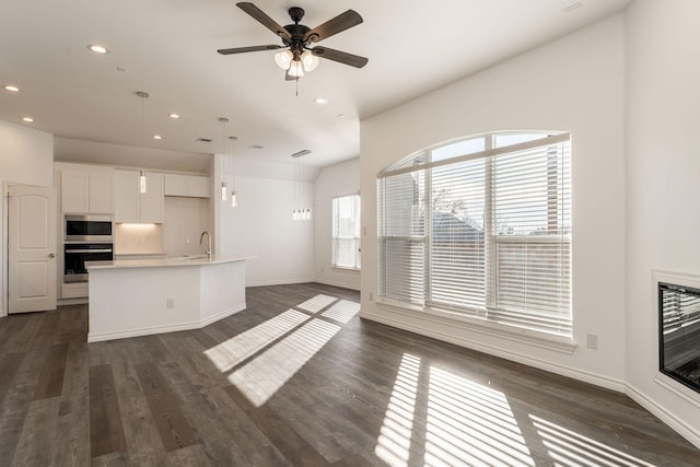 unfurnished living room with ceiling fan, sink, and dark hardwood / wood-style flooring