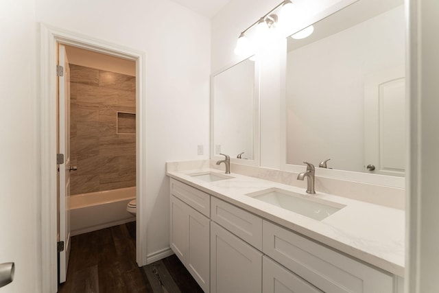 full bathroom with vanity, toilet, tiled shower / bath combo, and wood-type flooring