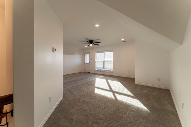 interior space with ceiling fan, vaulted ceiling, and dark colored carpet