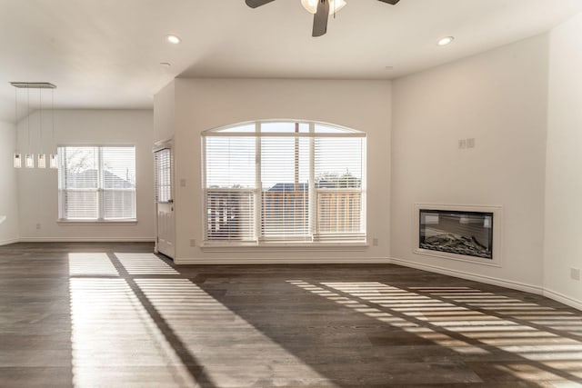 unfurnished living room featuring ceiling fan, dark hardwood / wood-style floors, and a wealth of natural light