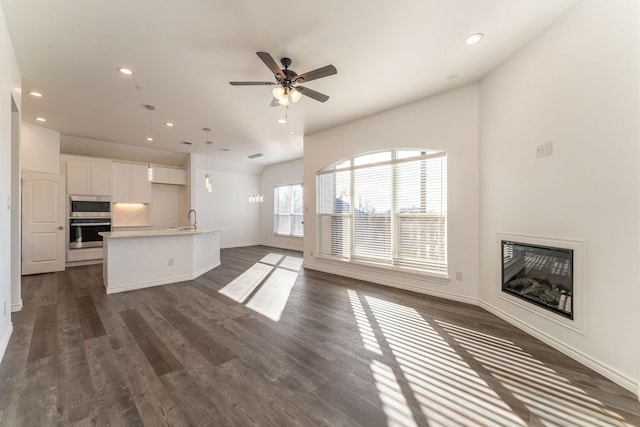 unfurnished living room with sink, dark hardwood / wood-style floors, and ceiling fan