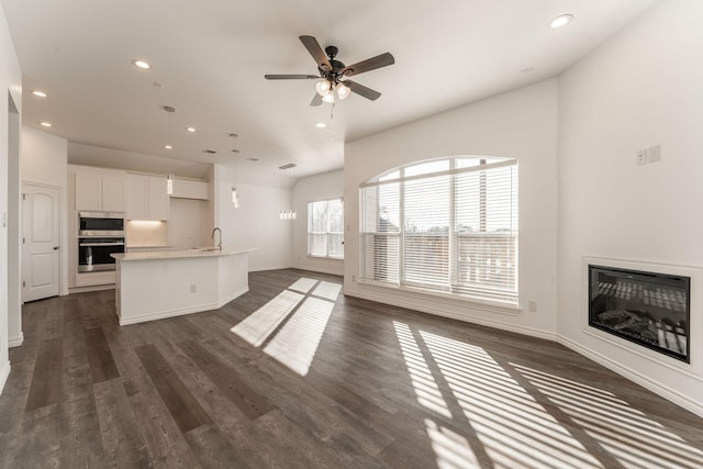 unfurnished living room featuring ceiling fan, sink, and dark hardwood / wood-style flooring