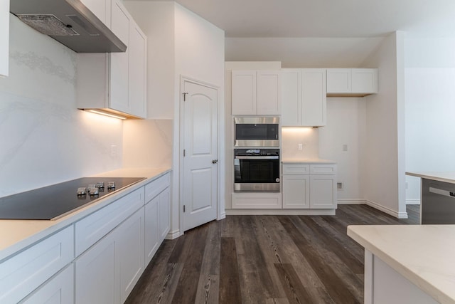 kitchen featuring appliances with stainless steel finishes, wall chimney exhaust hood, white cabinetry, dark hardwood / wood-style floors, and decorative backsplash