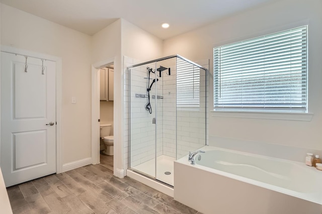 bathroom featuring wood-type flooring, shower with separate bathtub, and toilet