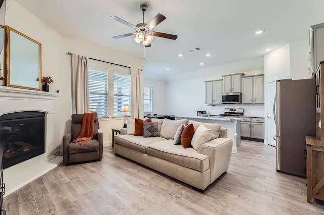 living room featuring ceiling fan and light hardwood / wood-style flooring