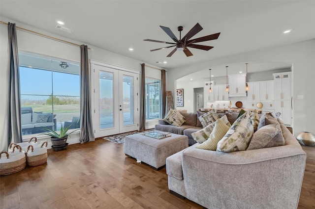 living room with hardwood / wood-style floors, ceiling fan, and french doors