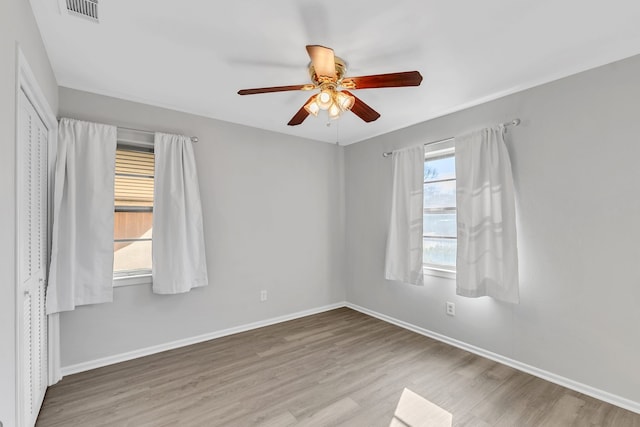 spare room featuring wood-type flooring, a wealth of natural light, and ceiling fan