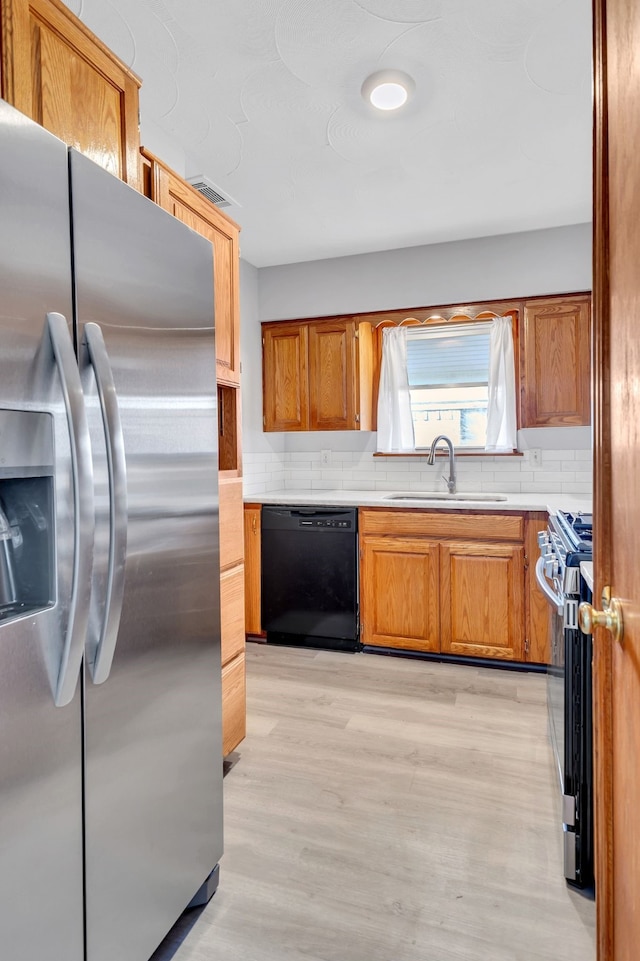 kitchen with light hardwood / wood-style floors, sink, backsplash, and appliances with stainless steel finishes