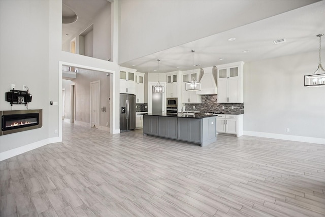 kitchen with tasteful backsplash, a chandelier, premium range hood, dark countertops, and appliances with stainless steel finishes