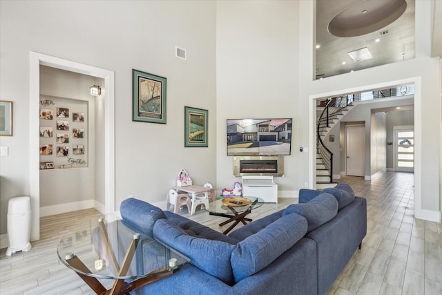 living room featuring light hardwood / wood-style floors and a towering ceiling