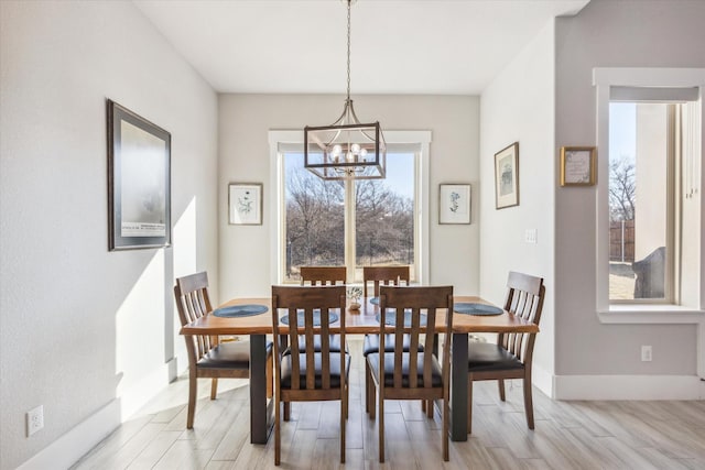 dining area with a chandelier, light wood-type flooring, and baseboards