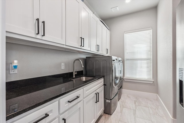 clothes washing area with cabinets, sink, and separate washer and dryer