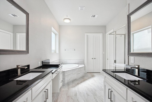 bathroom featuring a garden tub, a sink, and visible vents