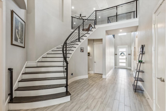 foyer with baseboards, recessed lighting, stairway, a towering ceiling, and light wood-style flooring