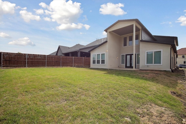 rear view of property with a yard, a fenced backyard, and stucco siding