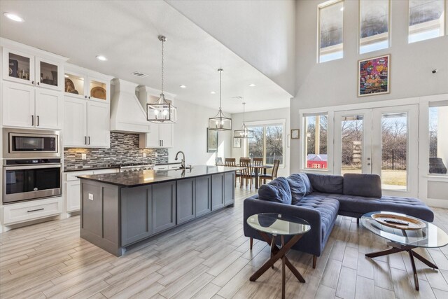 kitchen featuring tasteful backsplash, open floor plan, dark countertops, stainless steel appliances, and custom range hood