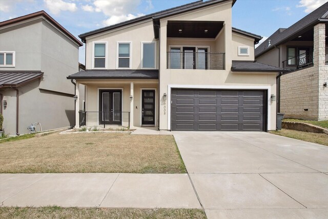 view of front of house with stucco siding, an attached garage, and covered porch