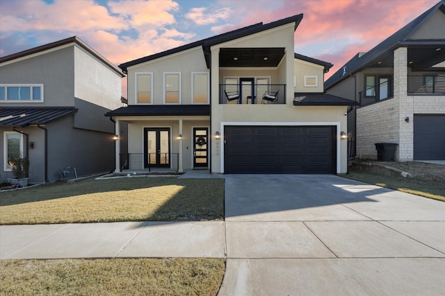 modern home with stucco siding, a balcony, french doors, a garage, and driveway