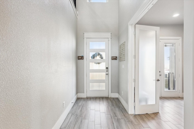 entryway with baseboards, plenty of natural light, a textured wall, and wood tiled floor