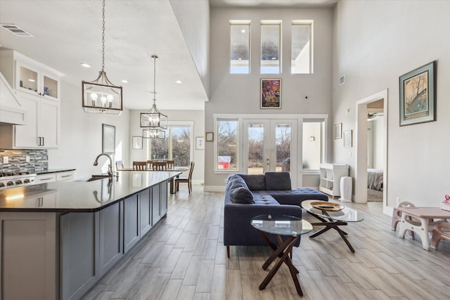 living room featuring sink, a chandelier, a towering ceiling, and french doors