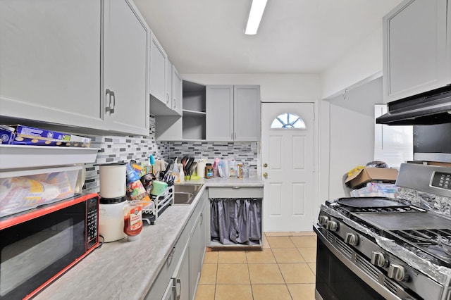 kitchen featuring gas stove, light tile patterned floors, tasteful backsplash, and gray cabinets