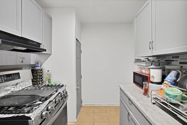 kitchen featuring white cabinets, stainless steel gas range, tasteful backsplash, and light tile patterned flooring