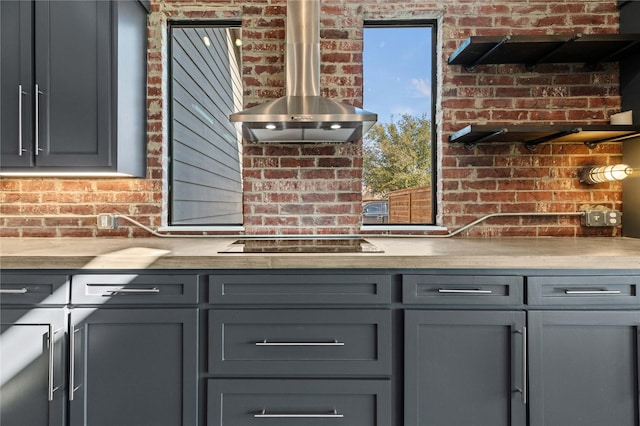 interior details with black electric cooktop and wall chimney exhaust hood