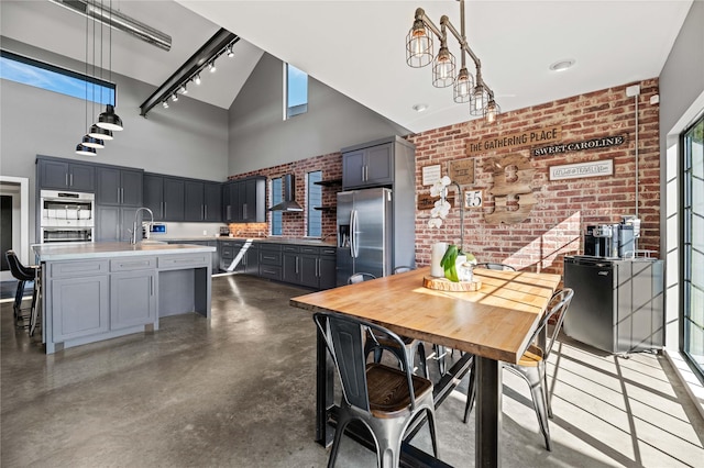 dining space featuring high vaulted ceiling, sink, and brick wall