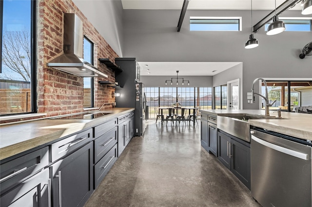 kitchen with hanging light fixtures, black electric cooktop, dishwasher, and wall chimney exhaust hood