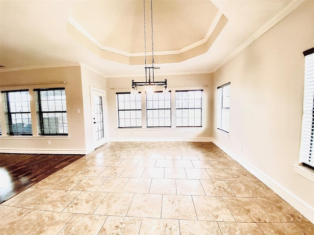 interior space featuring a raised ceiling, ornamental molding, a healthy amount of sunlight, and a notable chandelier