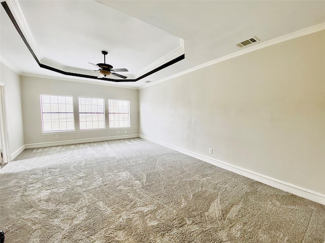 carpeted empty room featuring crown molding, ceiling fan, and a raised ceiling