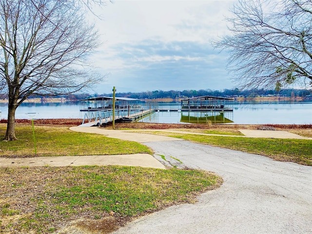 dock area with a lawn and a water view