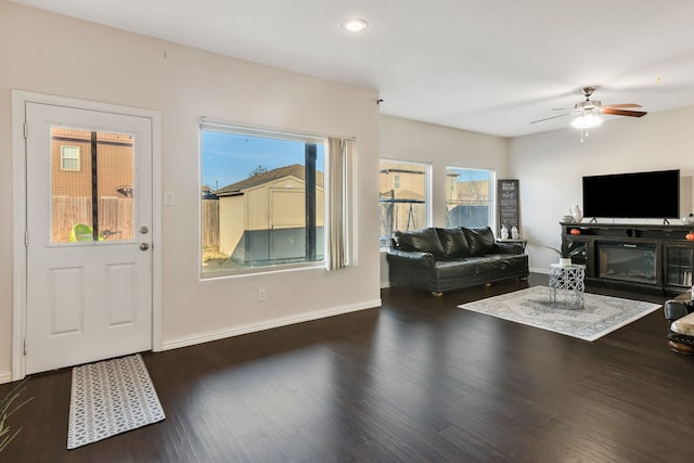 living room with ceiling fan and dark wood-type flooring