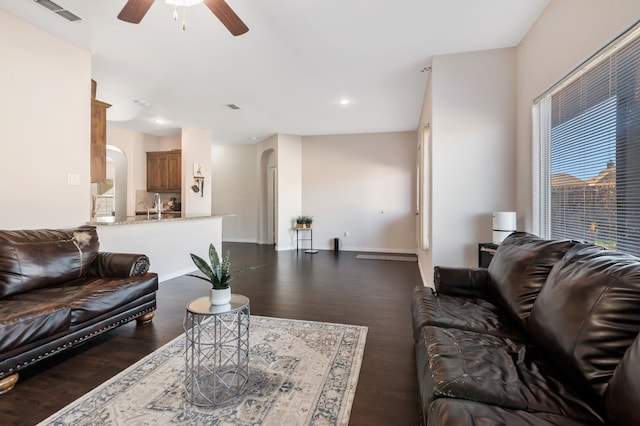 living room featuring dark wood-type flooring and ceiling fan