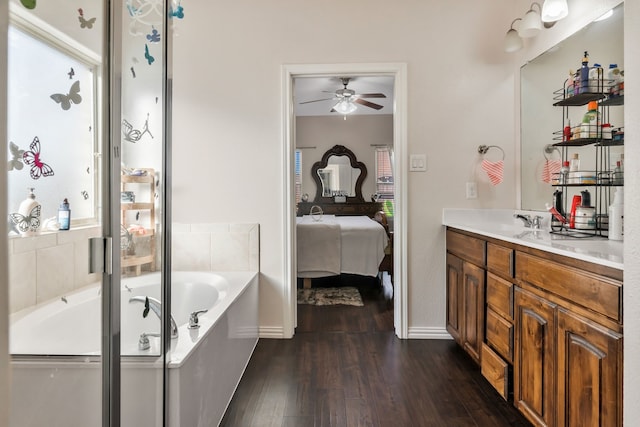 bathroom with hardwood / wood-style floors, vanity, ceiling fan, and a bathtub