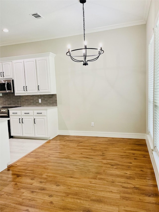 unfurnished dining area featuring ornamental molding, visible vents, a chandelier, and light wood-type flooring