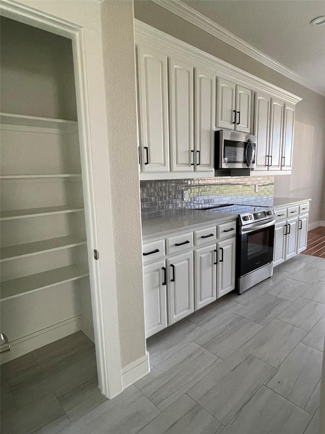 kitchen with white cabinetry, decorative backsplash, appliances with stainless steel finishes, light countertops, and ornamental molding