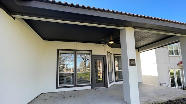 property entrance with stucco siding, a patio area, and a tile roof