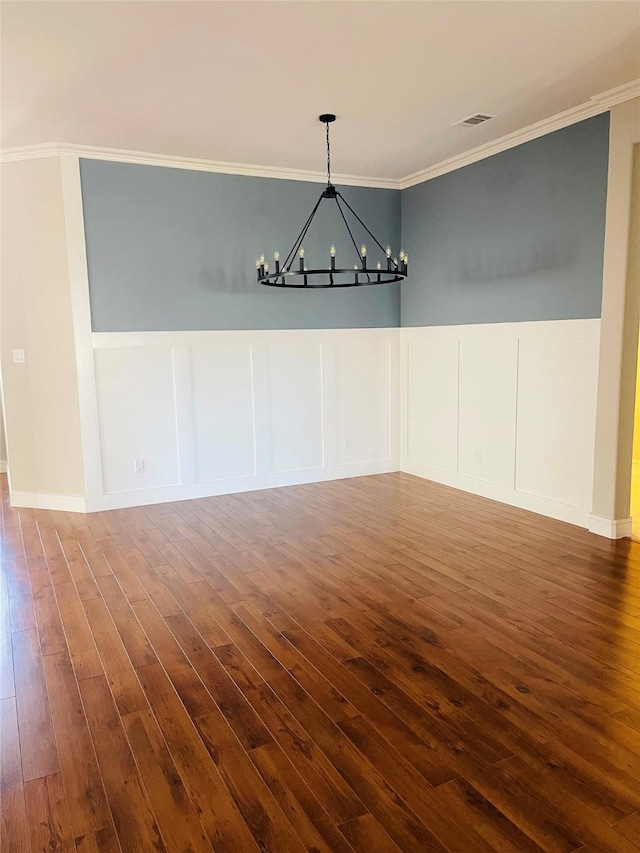 unfurnished dining area with a notable chandelier, ornamental molding, and dark hardwood / wood-style flooring