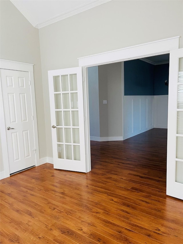 empty room with french doors, hardwood / wood-style floors, lofted ceiling, and crown molding