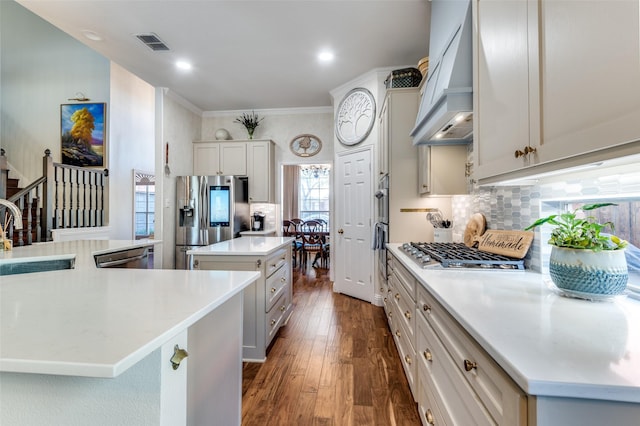 kitchen with a center island, appliances with stainless steel finishes, premium range hood, decorative backsplash, and sink