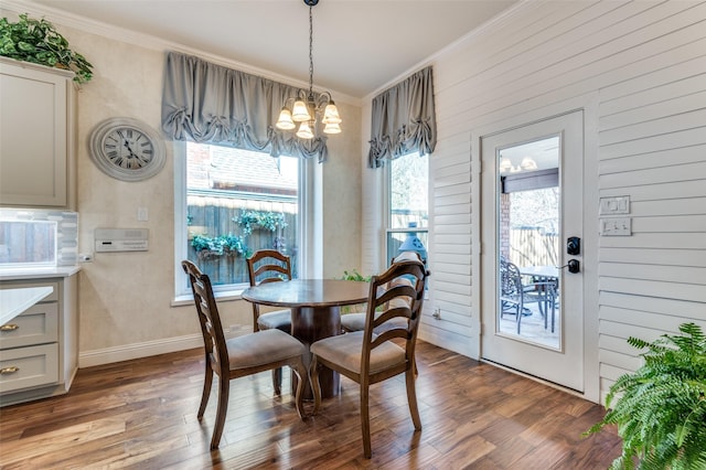 dining room featuring a chandelier, wood walls, ornamental molding, and hardwood / wood-style floors