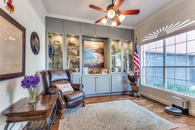 sitting room with ceiling fan, ornamental molding, and light wood-type flooring