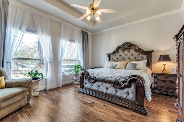 bedroom featuring ceiling fan, crown molding, dark hardwood / wood-style flooring, and a tray ceiling