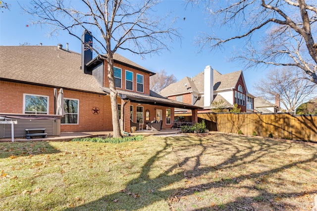 back of house featuring a hot tub, a yard, and a patio