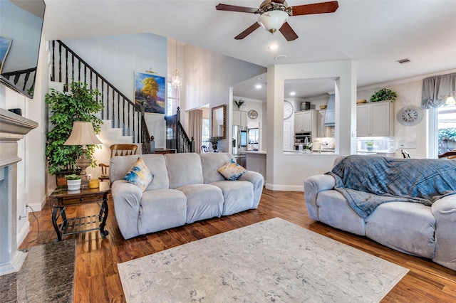 living room with ceiling fan with notable chandelier, ornamental molding, and wood-type flooring